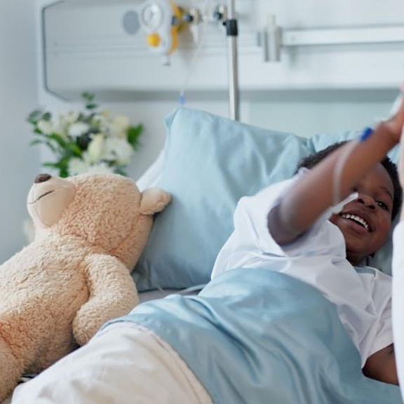 A nurse and a child patient share a cheerful high five